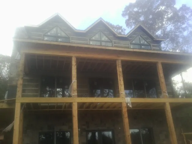 Dormers and porch framing on a large log home under construction — Roof Coating work by our crew in New River