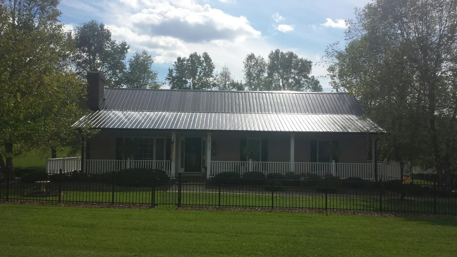 Gray metal roof on a brick ranch with a full width front porch — Gutter Guard Installation work by our crew in New River