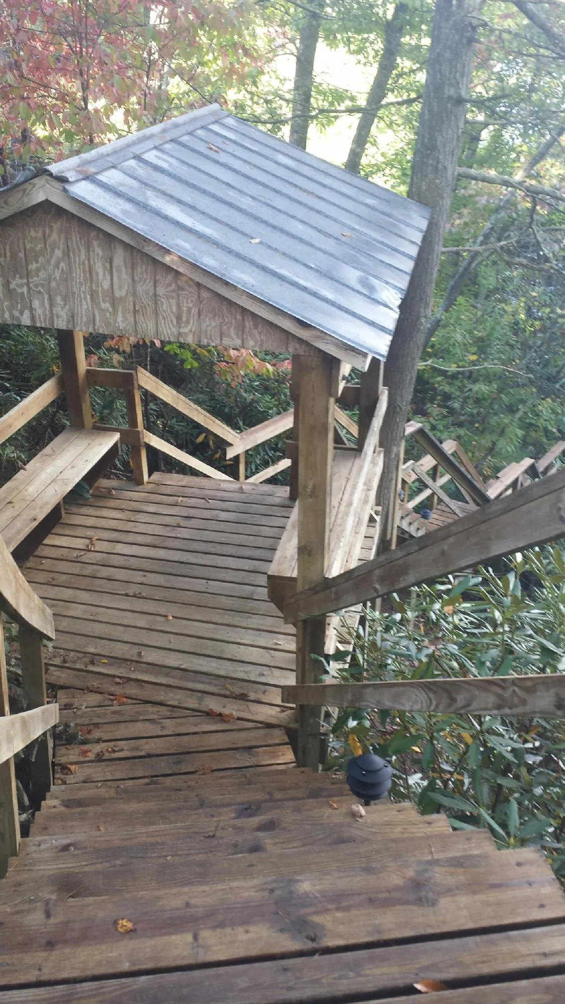 Metal roofed shelter over wooden steps on a wooded walkway — Skylight Repair & Installation work by our crew in New River