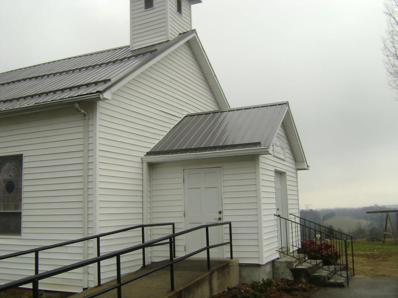 Gray metal roof on a white clapboard church with a steeple in New River